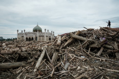 Flood aftermath: A man takes pictures on Dec. 13 as he stands on piles of uprooted trees swept away by a flash flood at Darul Mukhlisin Islamic boarding school in Aceh Tamiang, Aceh. Devastating floods and landslides have killed 1,006 people in Indonesia, rescuers said on Dec. 13 as the nation grapples with the huge scale of relief efforts.