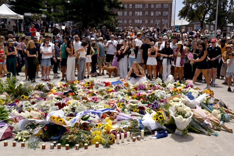 Mourners gather by floral tributes at the Bondi Pavillion in memory of the victims of a shooting at Bondi Beach, in Sydney on December 15, 2025. A father-and-son team toting long-barreled guns shot and killed 15 people including a 10-year-old girl at Sydney's Bondi Beach on December 14, with authorities labelling it an antisemitic terrorist attack on a Jewish festival. 