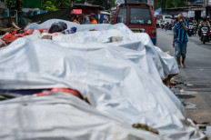Acute pollution: A resident covers his nose on Dec. 16, 2025, while walking past piles of garbage covered with tarps in Serpong, South Tangerang, Banten. The South Tangerang city administration covered the trash with tarps as a temporary measure to reduce odors during reorganization at the Cipeucang landfill, which has led to a temporary halt in waste transportation activities.