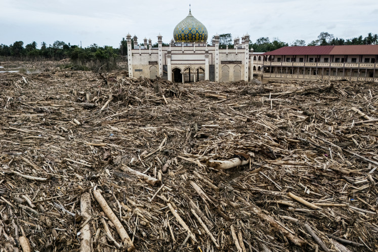 Standing proud: Piles of uprooted and felled trees swept down by a flash flood surround Darul Mukhlisin Islamic boarding school and the mosque attached to the school in Aceh Tamiang, Aceh, on Dec. 14, 2025..