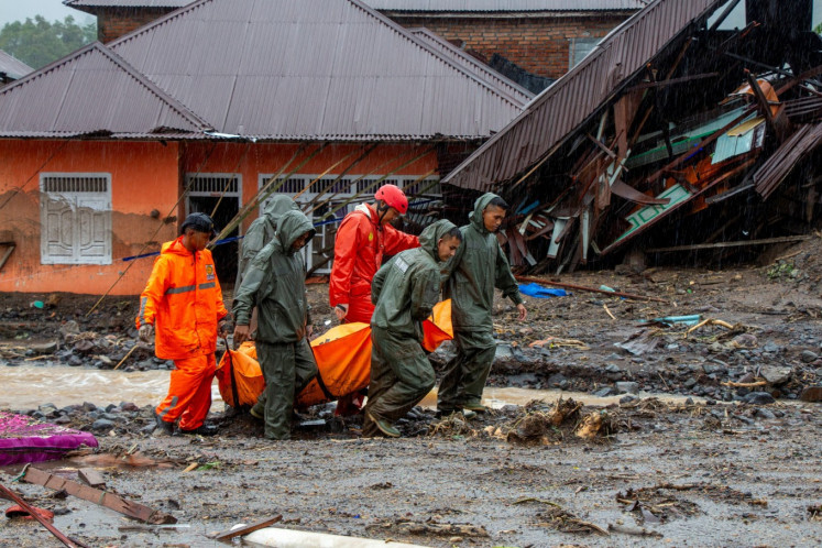 Rescuers carry a body bag of a victim recovered on Friday from an area hit by flash floods following heavy rains in Malalak District, Agam Regency, West Sumatra. 