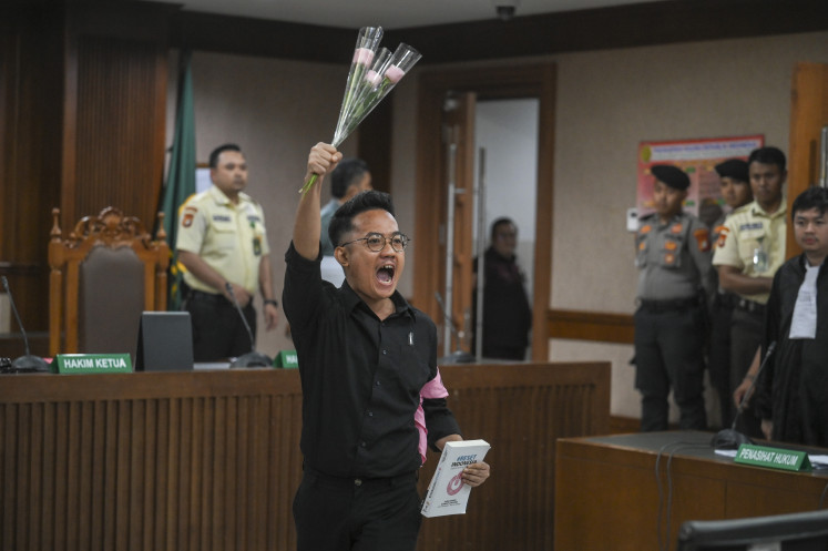 Lokataru executive director Delpedro Marhaen gestures after attending the reading of charges on Dec. 16 at the Central Jakarta District Court. Delpedro and three other co-defendants, Muzaffar Salim, Syahdan Husein and Khariq Anhar, have been charged with incitement for allegedly posting social media content related to demonstrations in August that turned violent after a delivery driver was ran over and killed by police.