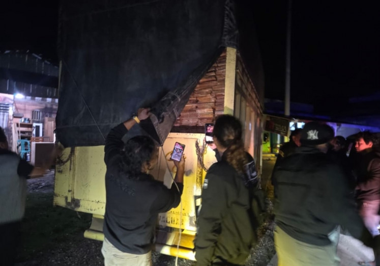 Detectives from the Kuantan Singingi Police inspect the back of a Mitsubishi Canter truck carrying illegal timber products in Koto Kari village, Kuantan Singingi regency, Riau, on Dec. 11, 2025. 