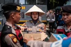 Police officers deliver water bottles to rallygoers on Sept. 24, 2025, during a demonstration on National Farmers' Day in Jakarta.