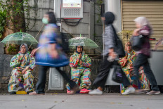 Pedestrians walk past activists taking part in a sit-in on Dec. 10, 2024, to raise awareness of gender-based violence in Jakarta 