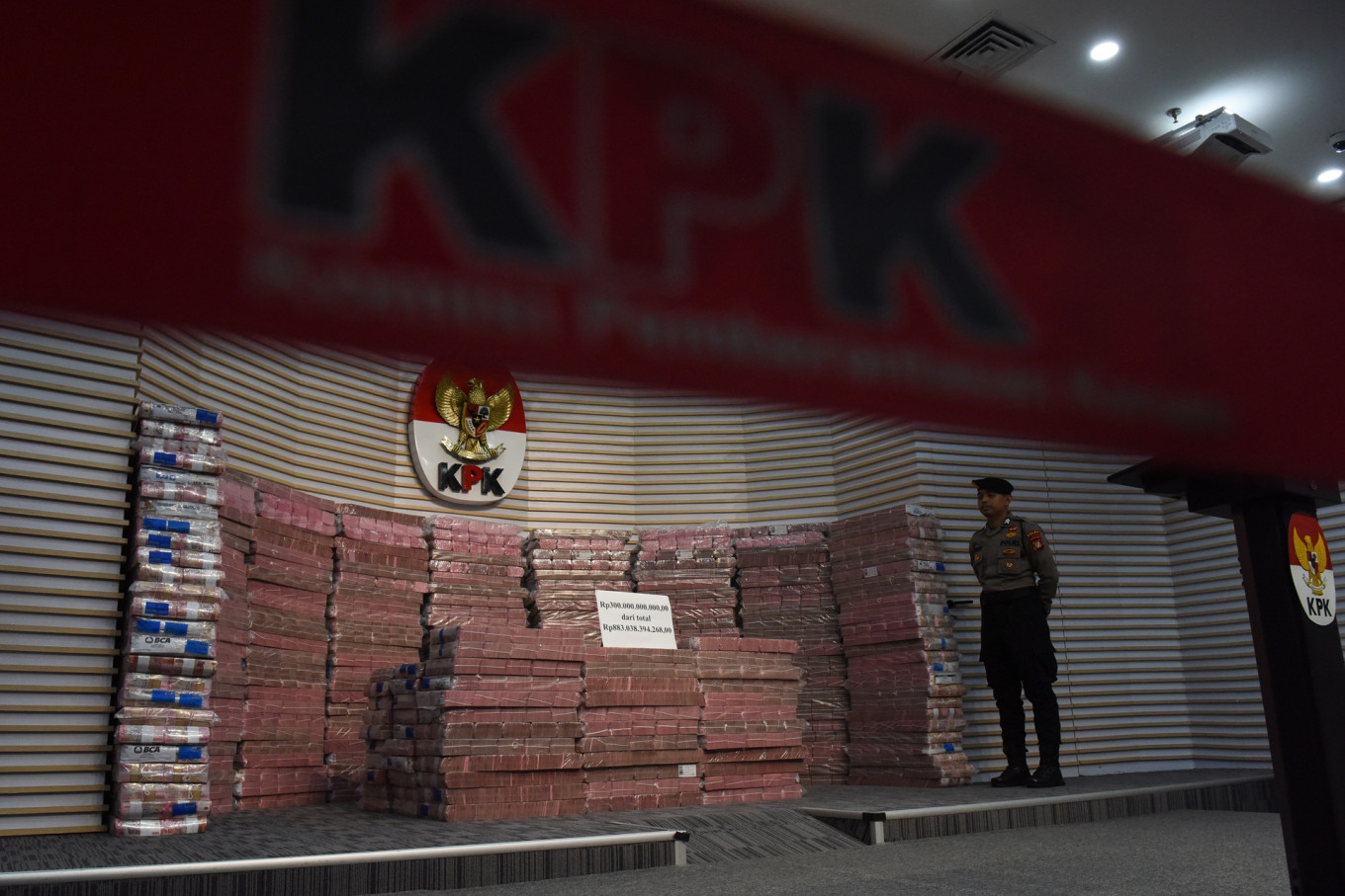 A police officer stands guard next to a stack of rupiah banknotes at the Corruption Eradication Commission (KPK) headquarters on Nov. 20 in Jakarta. The money represents the Rp 883 billion (US$5 million) of state losses recovered from a corruption case pertaining to the fund management at state-owned insurer PT Taspen.