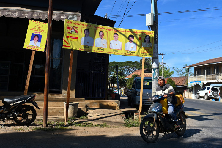 A motorcyclist rides past an election campaign banner on Dec. 9, 2025, in Nawnghkio, Shan state, ahead of the first phase of Myanmar&rsquo;s general election set to take place on Dec. 28.
