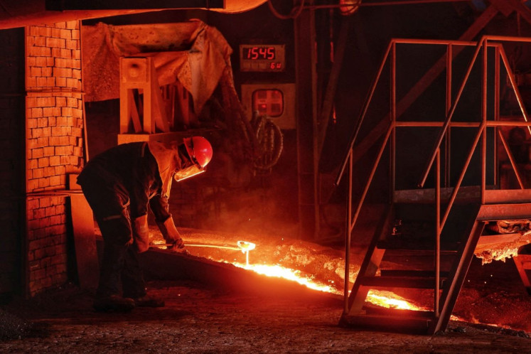 Playing with fire: A worker in protective gear uses a tool to scoop molten metal on Sept. 16, 2025 at Harita Nickel&rsquo;s smelting facility on Obi Island in South Halmahera, North Maluku.