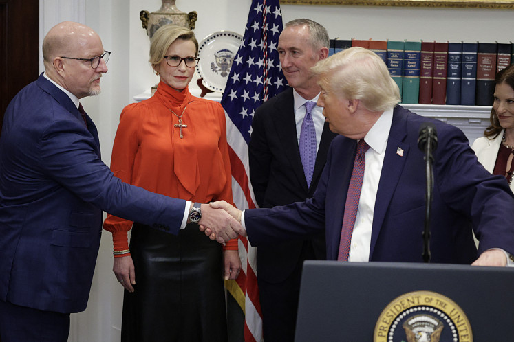 US President Donald Trump shakes hands with Merck CEO Robert Davis (left) during an event in the Roosevelt Room of the White House Dec. 19, 2025, in Washington, DC. Trump delivered remarks on lowering prescription drug prices during the event.