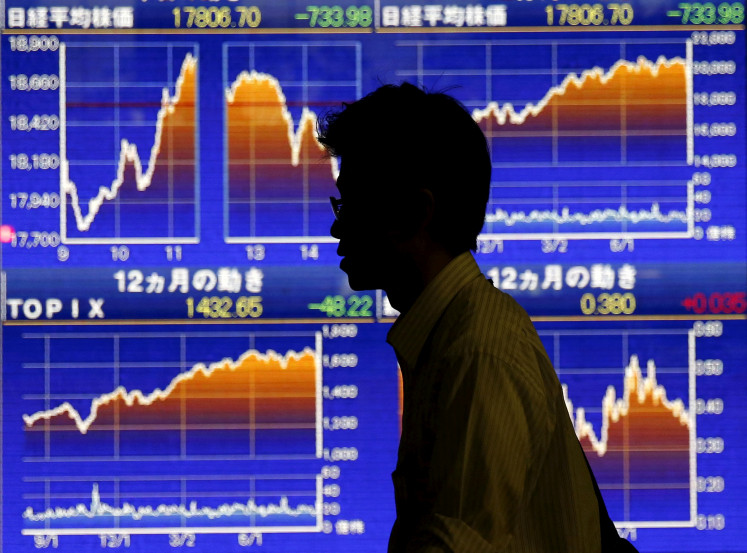 A man walks past in front of graphs showing recent Japan's Nikkei share average outside a brokerage in Tokyo on Aug. 25, 2015.