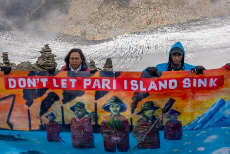 Arif Pujianto, a resident of Pulau Pari Island, and Suci Fitriah Tanjung of Indonesian NGO Walhi hold a banner on Eggishorn mountain, near Aletsch glacier, before a Swiss court's expected decision whether to accept a legal complaint filed by Indonesian residents against major cement manufacturer Holcim, headquartered in Switzerland, which they say is doing &ldquo;too little&ldquo; to cut carbon emissions, in Fiesch, Switzerland, Aug. 30, 2025.