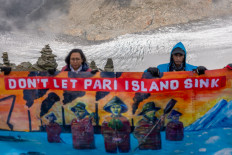 Arif Pujianto, a resident of Pulau Pari Island, and Suci Fitriah Tanjung of Indonesian NGO Walhi hold a banner on Eggishorn mountain, near Aletsch glacier, before a Swiss court's expected decision whether to accept a legal complaint filed by Indonesian residents against major cement manufacturer Holcim, headquartered in Switzerland, which they say is doing &ldquo;too little&ldquo; to cut carbon emissions, in Fiesch, Switzerland, Aug. 30, 2025.