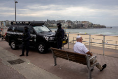Riot police stand by on Sunday, Dec. 21, 2025, while a Jewish man sits on a bench at Bondi Beach, where thousands attended a vigil for victims and survivors of a deadly mass shooting during a Jewish Hanukkah celebration at Bondi Beach on Dec. 14, in Sydney, Australia.