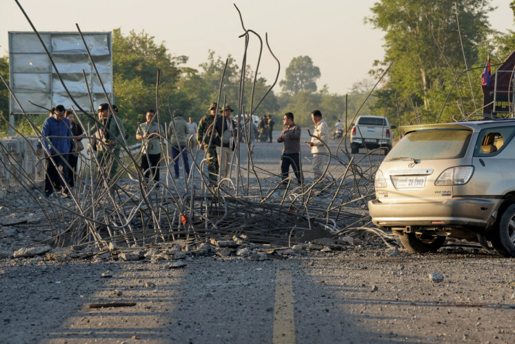 People look at a damaged bridge after Thailand carried out air strikes in an area between Cambodia's Oddar Meanchey and Siem Reap provinces on December 20, 2025.