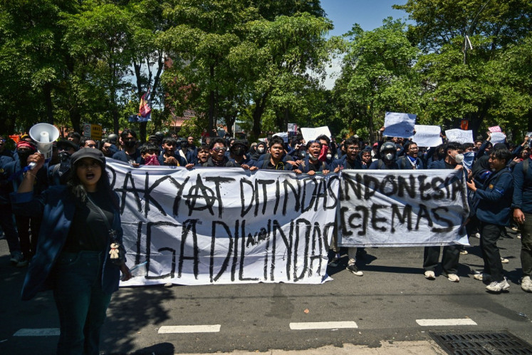 Demonstrators hold banners that read &ldquo;The people are oppressed and also run over&ldquo; (left) and &ldquo;Indonesia Cemas&ldquo; (Anxious Indonesia) right during a protest against police brutality in Surabaya, East Java on Aug. 30, 2025, following the death of an 'ojol' (online motorcycle transportation) driver who was run over by a police armored vehicle on Aug. 28 in Jakarta.