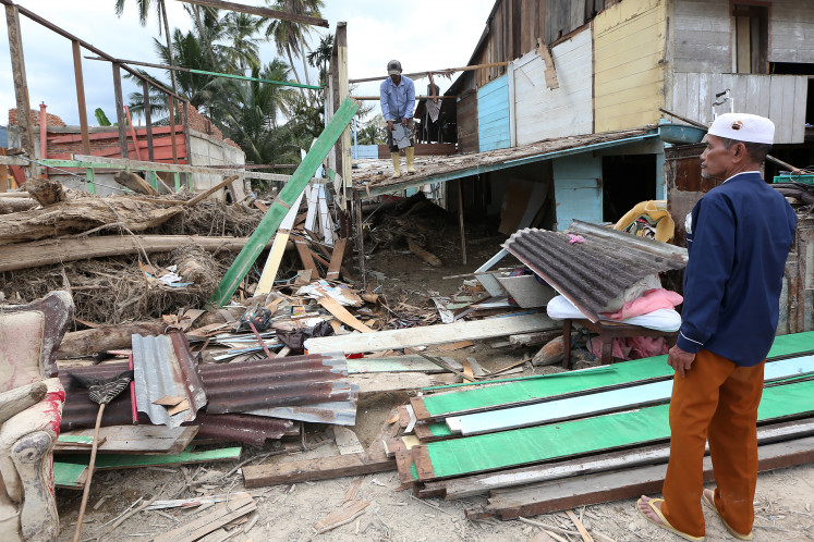 Cleanup time: A man cleans a home and salvages household belongings on Dec. 22, 2025, as another man looks on, in the aftermath of flooding in Lokop, East Aceh regency, Aceh.