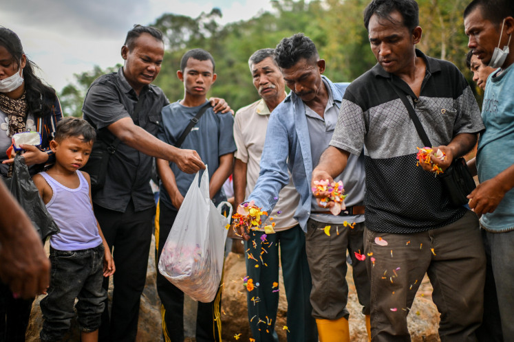 Local residents and families of people who went missing in the recent flash floods and landslides scatter flowers during a symbolic burial service on Dec. 23, 2025, in Hutanabolon, a subdistrict of Tukka district in Central Tapanuli regency, North Sumatra.
