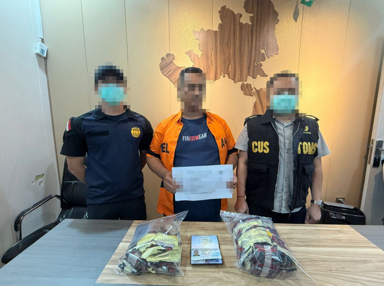 Two officers from the Batam Customs and Excise Office flank a man (center) suspected of trying to smuggle 148 vape pods containing the anesthetic drug etomidate from Malaysia to Indonesia via Batam&rsquo;s Harbour Bay ferry terminal in the Riau Islands on Dec. 17, 2025, in this undated picture.

