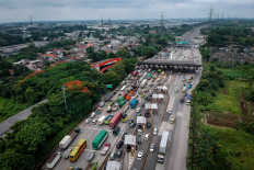 A variety of vehicles, including buses and freight trucks, stand in line on Dec. 24, 2025, at the Cikupa Tollgate in Tangerang regency, Banten.