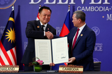 Thailand's Prime Minister Anutin Charnvirakul (left) and Cambodia's Prime Minister Hun Manet shake hands and hold up a document during the signing of a ceasefire deal between Cambodia and Thailand on the sidelines of the 47th ASEAN summit in Kuala Lumpur, Malaysia, on Oct. 26, 2025.