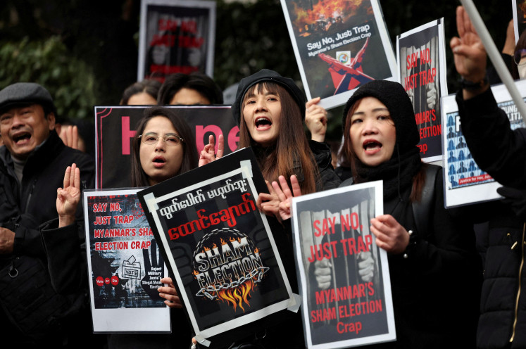 Myanmar protesters residing in Japan hold placards and raise three-finger salutes during a rally denouncing an upcoming election led by the military junta and demanding the immediate release of Myanmar's detained former leader Aung San Suu Kyi and all political prisoners, outside Myanmar's embassy in Tokyo, Japan, on Dec. 14, 2025.