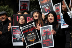 Myanmar protesters residing in Japan hold placards and raise three-finger salutes during a rally denouncing an upcoming election led by the military junta and demanding the immediate release of Myanmar's detained former leader Aung San Suu Kyi and all political prisoners, outside Myanmar's embassy in Tokyo, Japan, on Dec. 14, 2025.