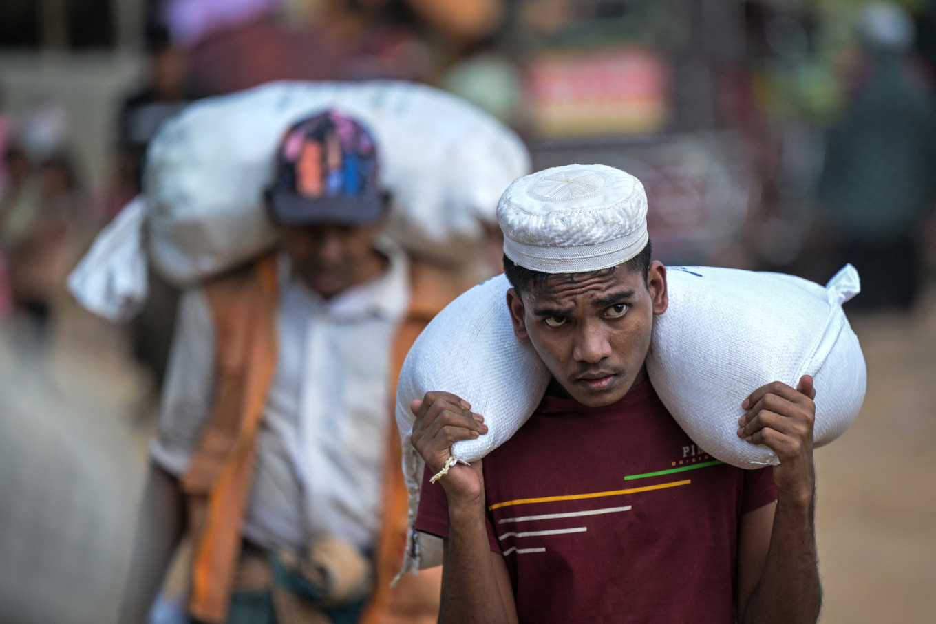 This photograph taken on Dec. 17, 2025 shows a Rohingya refugee carrying relief materials after collecting them from a distribution point at the Kutupalong refugee camp in Bangladesh's Ukhia.
Myanmar's military portrays its general election as a path to democracy and peace, but the vote offers neither to a million Rohingya exiles, robbed of citizenship rights and evicted from their homeland by force.