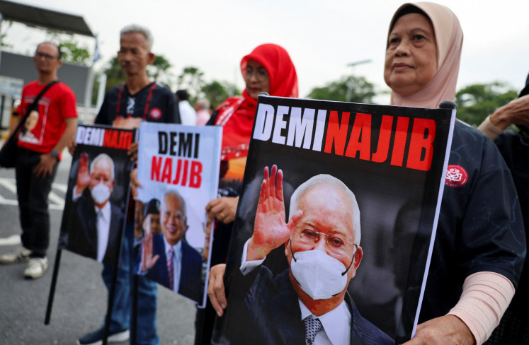 Supporters of former Malaysian prime minister Najib Razak hold banners featuring his portrait outside the Palace of Justice, as the high court will deliver its verdict on Najib for four corruption charges and 21 counts of money laundering involving the illegal transfer of about 2.2 billion ringgit (US$539 million) from 1Malaysia Development Berhad (1MDB), in Putrajaya, Malaysia on Dec. 26, 2025.