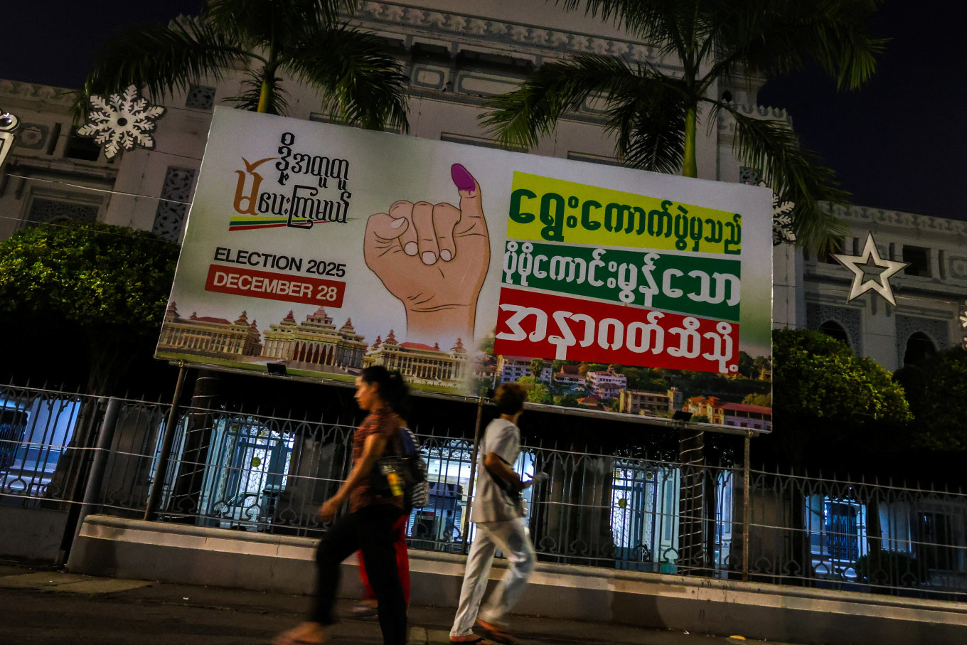 People walk past an election banner ahead of a general election in Thingangyun Township, Yangon, Myanmar, on Dec. 27, 2025.