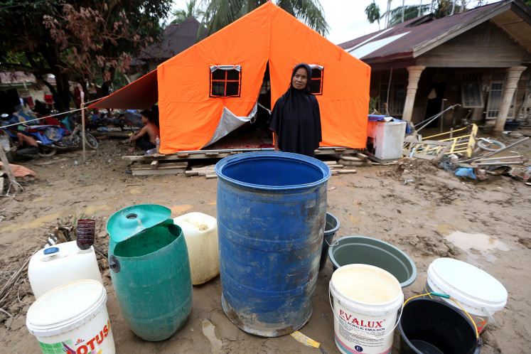 A woman waits for clean water on Dec. 28 in Lubuk Sidup village, Aceh Tamiang, Aceh. 32 days after flash floods caused by the overflow of the Tamiang River, access to clean water and sanitation remains an urgent problem for residents and evacuees in Aceh Tamiang regency, despite ongoing efforts by the government and nonprofits to respond to needs.