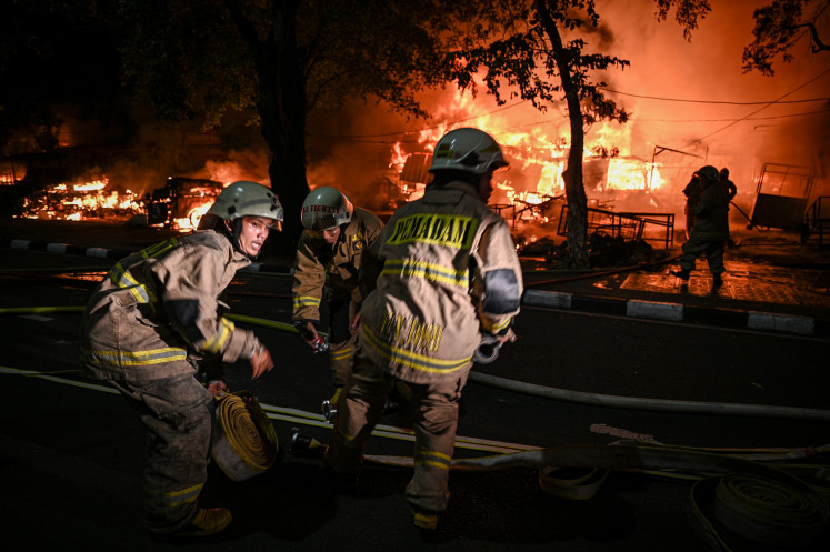 Firefighters are shown preparing to extinguish burning vendor stalls during unrest in Jakarta, in this file photo taken on Dec. 11, 2025.