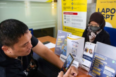 A taxpayer takes a picture of the guideline for requesting online taxation services on Nov. 20, 2023, at a counter at the Kebayoran Baru 1 branch of the tax office in South Jakarta. 