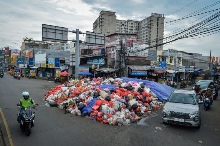 Vehicles pass by piles of garbage in Ciputat, South Tangerang, Banten, on Dec. 26, 2025. The city administration has declared a waste management emergency, in effect from Dec. 23, 2025, to Jan. 5, 2026, to accelerate cleanup efforts and mitigate the impact on residents&rsquo; health. 