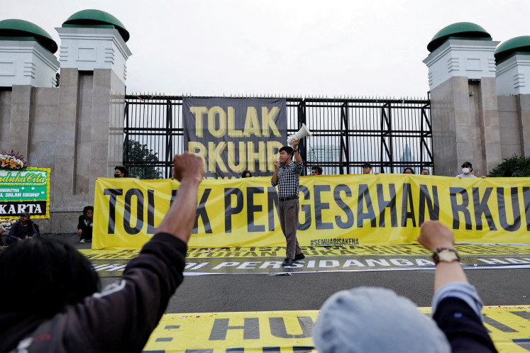 An activist shouts slogans during a protest outside the Senayan legislative complex in Central Jakarta on Dec. 5, 2022 as the House of Representatives is set to pass a new Criminal Code (KUHP) that will ban sex outside marriage, cohabitation between unmarried couples, insulting the president and expressing views counter to the national ideology.