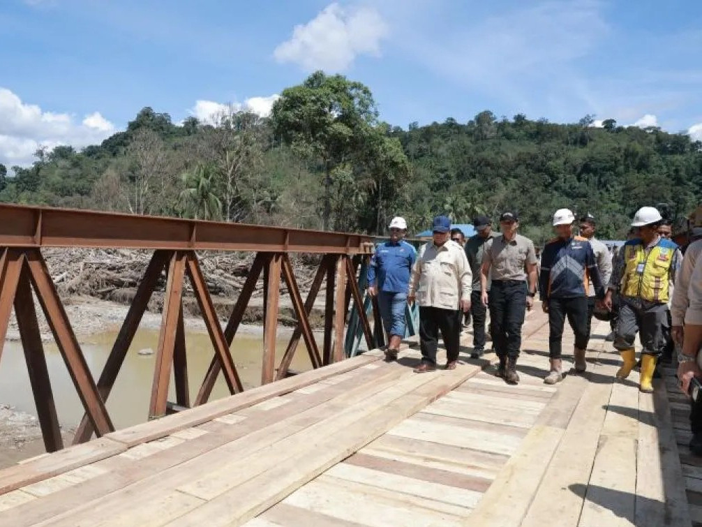 President Prabowo Subianto (second left) and Coordinating Infrastructure and Regional Development Minister Agus Harimurti Yudhoyono (center) cross a Bailey bridge on Dec. 31, 2025, over Garoga River in Batang Toru, South Tapanuli, North Sumatra. 
