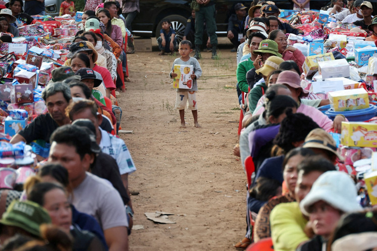 A boy holding a supply stands among people waiting to collect supplies at Batthkav refugee camp in Chong Kal, Oddar Meanchey Province, Cambodia, on Dec. 12, 2025, amid clashes between Thailand and Cambodia along a disputed border area.