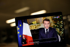 French President Emmanuel Macron appears on a screen as he delivers his New Year's speech to the nation at the Elysee Palace in Paris, France, on Dec. 31, 2025.