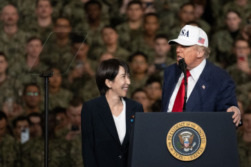 Japan's Prime Minister Sanae Takaichi (left) looks on United States President Donald Trump as he delivers a speech in front of US Navy personnel on board the US Navy's USS George Washington aircraft carrier at the US naval base in Yokosuka, Japan on Oct. 28, 2025.