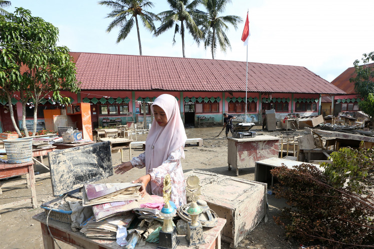 A teacher cleans up books and teaching equipment covered in mud on Jan. 4 at state elementary school SD Negeri 11 Kuta Blang in Keurumbok, Bireuen, Aceh, following recent flash floods hitting northern Sumatra. The Elementary and Secondary Education Ministry said 3,508 of 4,149 schools affected by hydrometeorological disasters in North Sumatra, West Sumatra and Aceh were ready to resume classes for the second semester starting on Monday.