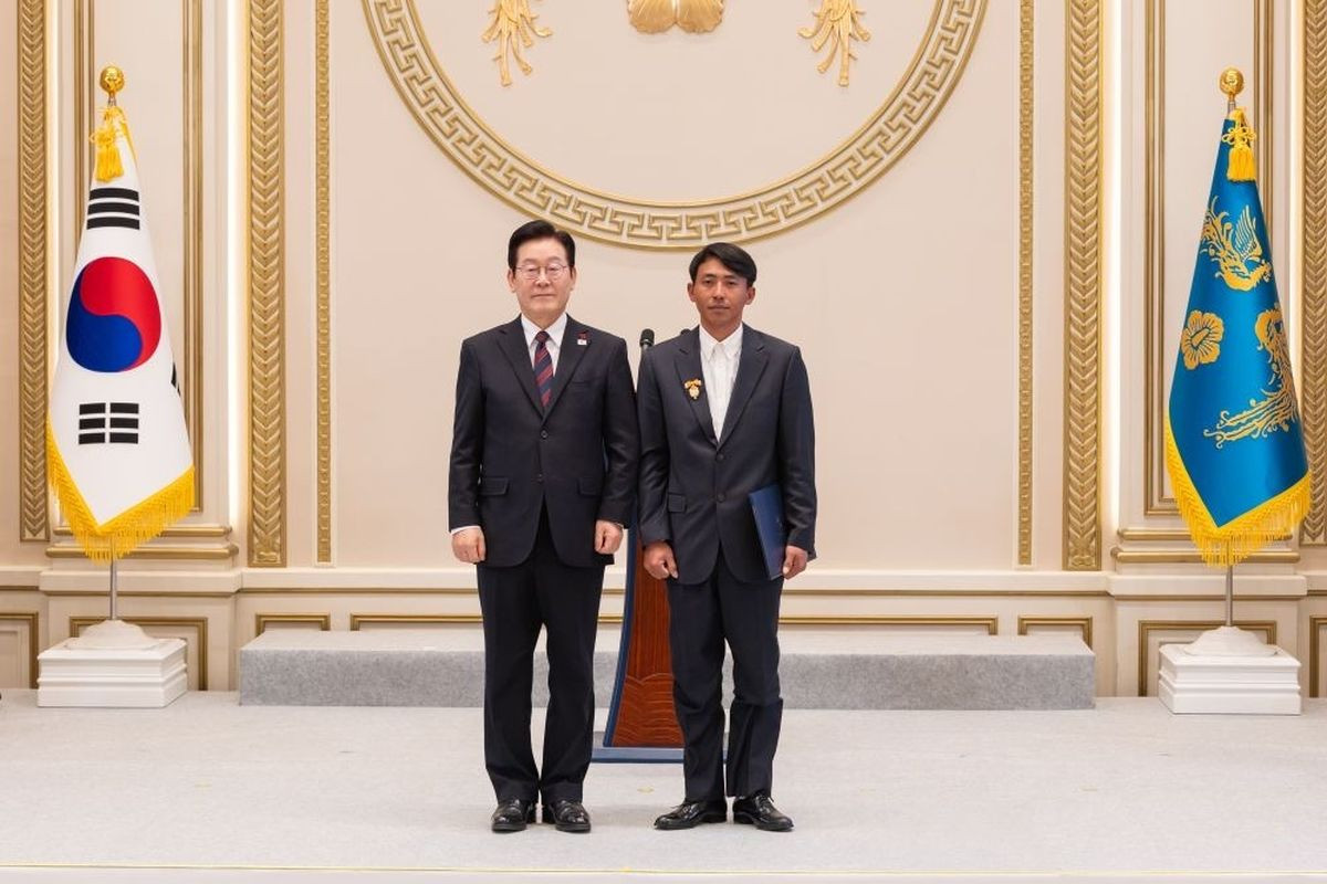 Indonesian migrant worker Sugianto stands next to South Korean President Lee Jae-myung on Dec. 2, 2025, during an award ceremony at the Blue House in Seoul. Sugianto received a presidential honor for his bravery in rescuing elderly residents during a massive forest fire in South Korea in March 2025.