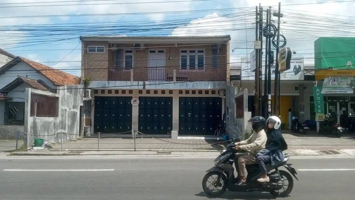 A motorcyclist and his passenger drive past an empty shop-house on Jl. Gito Gati in Donorhajo village, Ngaglik district, of Yogyakarta&rsquo;s Sleman regency on Jan. 6, 2026, the day after the Yogyakarta City Police raided the facility on suspicion it was being used as a base of operations for international scams.