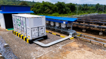 The Containerized Battery Energy Storage System (CBESS) developed by solar power developer SUN Energy is seen bext to a solar panel farm (right) in Feb. 2025 at the site of coal mining contractor PT Cipta Kridatama in Maura Bungo, Jambi.