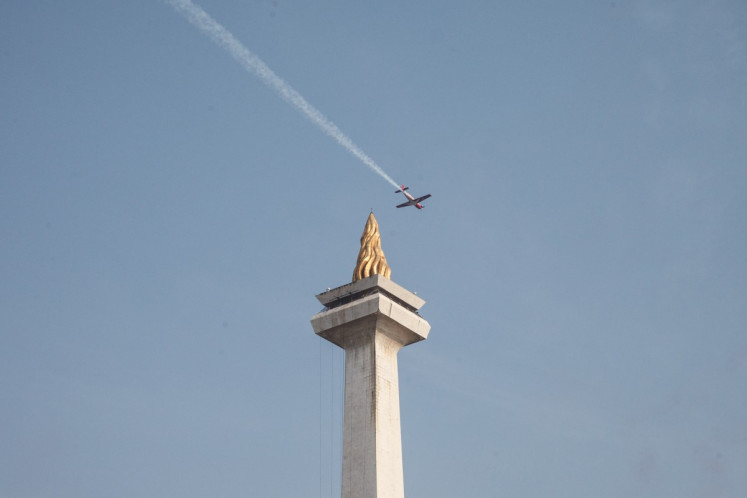 An Indonesian Air Force plane from the Jupiter aerobatic team flies past the National Monument (Monas) during a parade on Oct. 5, 2025, held as part of celebrations marking the Indonesian Military's (TNI) 80th anniversary at Merdeka Square in Central Jakarta.