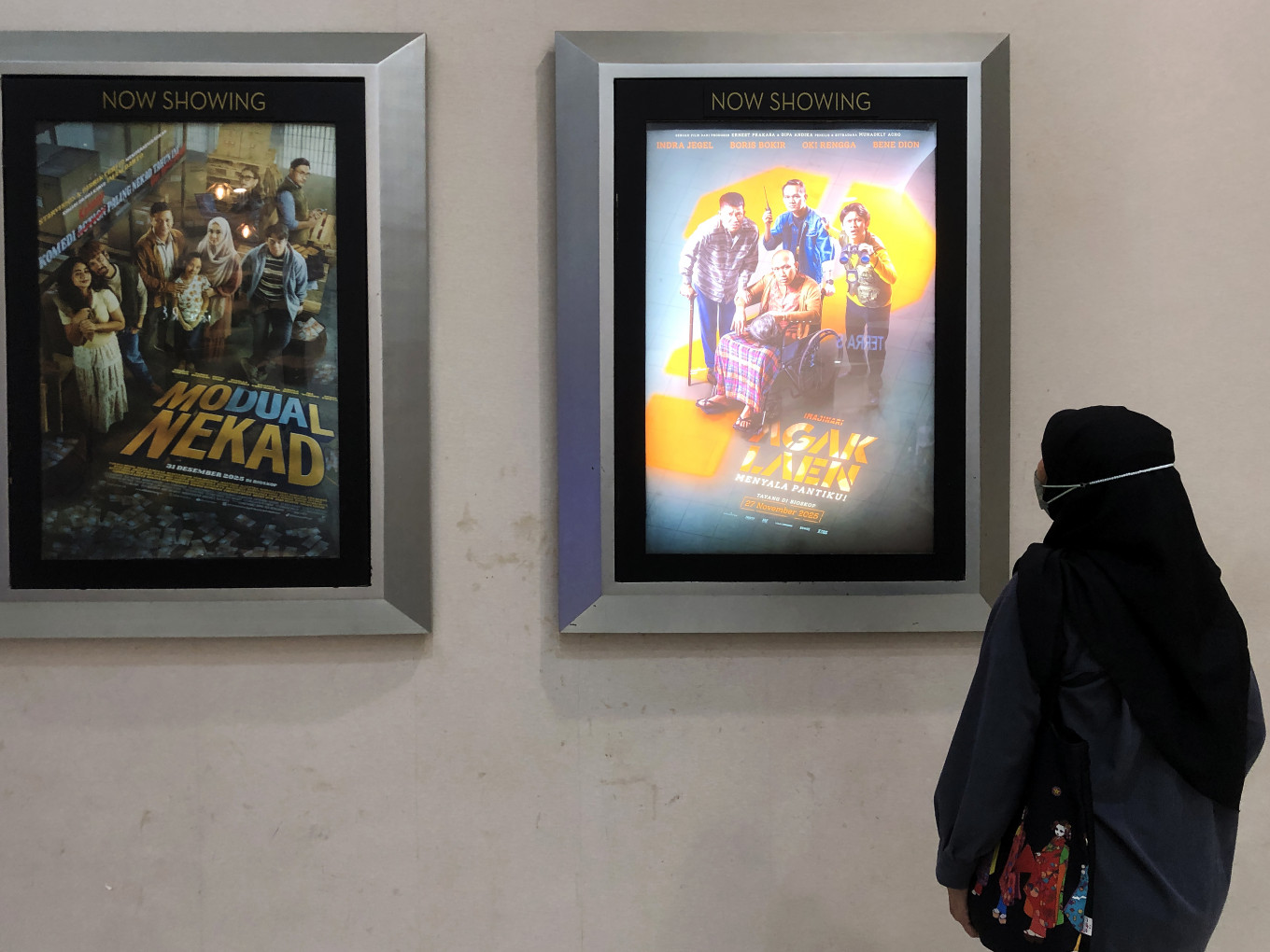Laughter therapy: A woman looks on Jan. 6, 2026, at the film Agak Laen: Menyala Pantiku! poster listed under the &ldquo;Now Showing&rdquo; category at a Cinema XXI theater in a shopping mall in East Jakarta.