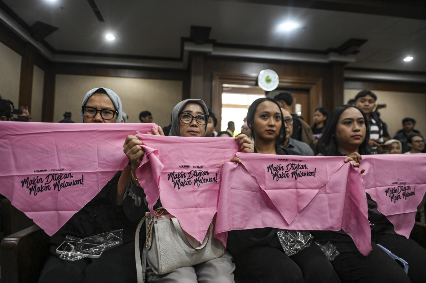 Women holds cloths that read &ldquo;Makin Ditekan Makin Dilawan&ldquo; (The more pressure, the more the fight) ahead of the indictment hearing on Dec. 16, 2025, against Delpedro Marhein, executive director of rights group Lokataru Foundation, at the Central Jakarta District Court. Prosecutors indicted Delpedro for allegedly inciting hostility toward the government and encouraging students, including minors, to take part in riots.
