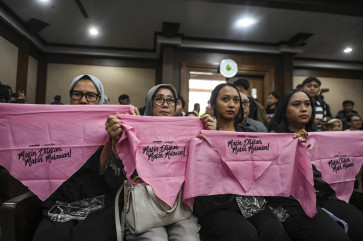 Women holds cloths that read &ldquo;Makin Ditekan Makin Dilawan&ldquo; (The more pressure, the more the fight) ahead of the indictment hearing on Dec. 16, 2025, against Delpedro Marhein, executive director of rights group Lokataru Foundation, at the Central Jakarta District Court. Prosecutors indicted Delpedro for allegedly inciting hostility toward the government and encouraging students, including minors, to take part in riots.