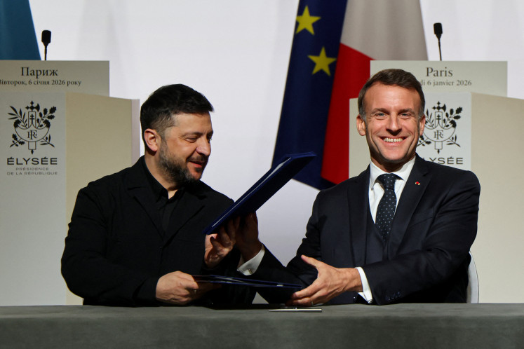 Ukraine&rsquo;s President Volodymyr Zelenskiy (left) and France&rsquo;s President Emmanuel Macron react on Jan. 6, 2026, upon the signing of the declaration on deploying a post-ceasefire force in Ukraine during the so-called &ldquo;Coalition of the Willing&rdquo; summit, at the Elysee Palace in Paris.