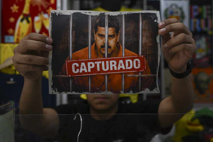 A man shows an image featuring a digitally altered image of the ousted Venezuelan President Nicolas Maduro before printing it on a shirt for sale at &ldquo;Emporio Comercial de Gamarra&ldquo; in Lima on Jan. 6, 2026.