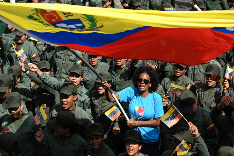 A woman waves a Venezuelan flag among members of the National Bolivarian Armed Forces during a rally on Jan. 6, 2026, in support of seized Venezuela President Nicolas Maduro and his wife Cilia Flores, in Caracas. United States forces reportedly killed 55 Venezuelan and Cuban military personnel in the raid to capture Maduro. 