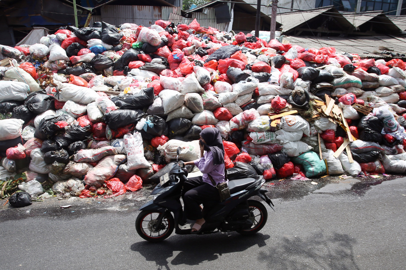 A motorist passes by piles of garbage on Jl. Raya Otista in Cimanggis, South Tangerang, Banten, on Jan. 6, 2026. The South Tangerang city administration has struggled to manage the accumulating waste, which has persisted for the past month.